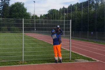 Monteure montieren das Firmenschild am Ballfangzaun – der letzte Arbeitsschritt